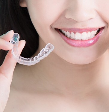 woman holding up a clear aligner