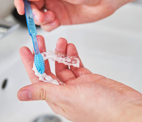 person cleaning their clear aligners