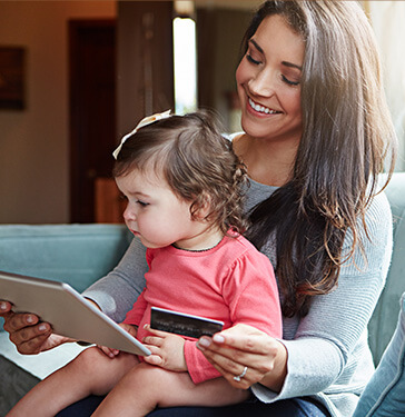 woman holding her infant daughter in her lap while paying a bill online
